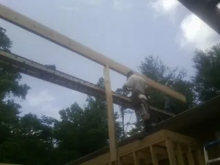 Carpenter setting a ridge beam over a new addition frame — Ice Dam Removal by Roofing Brothers in Newberry