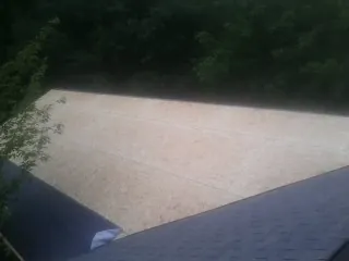 New OSB roof sheathing installed beside an existing shingle roof in Newberry