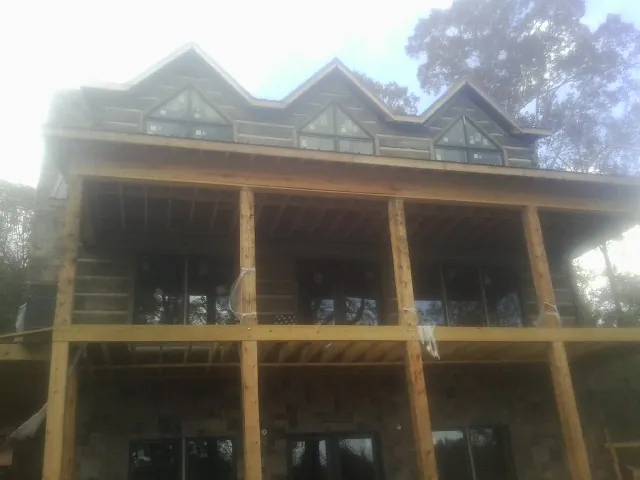 Dormers and porch framing on a large log home under construction — Roof Coating work by our crew in Newberry