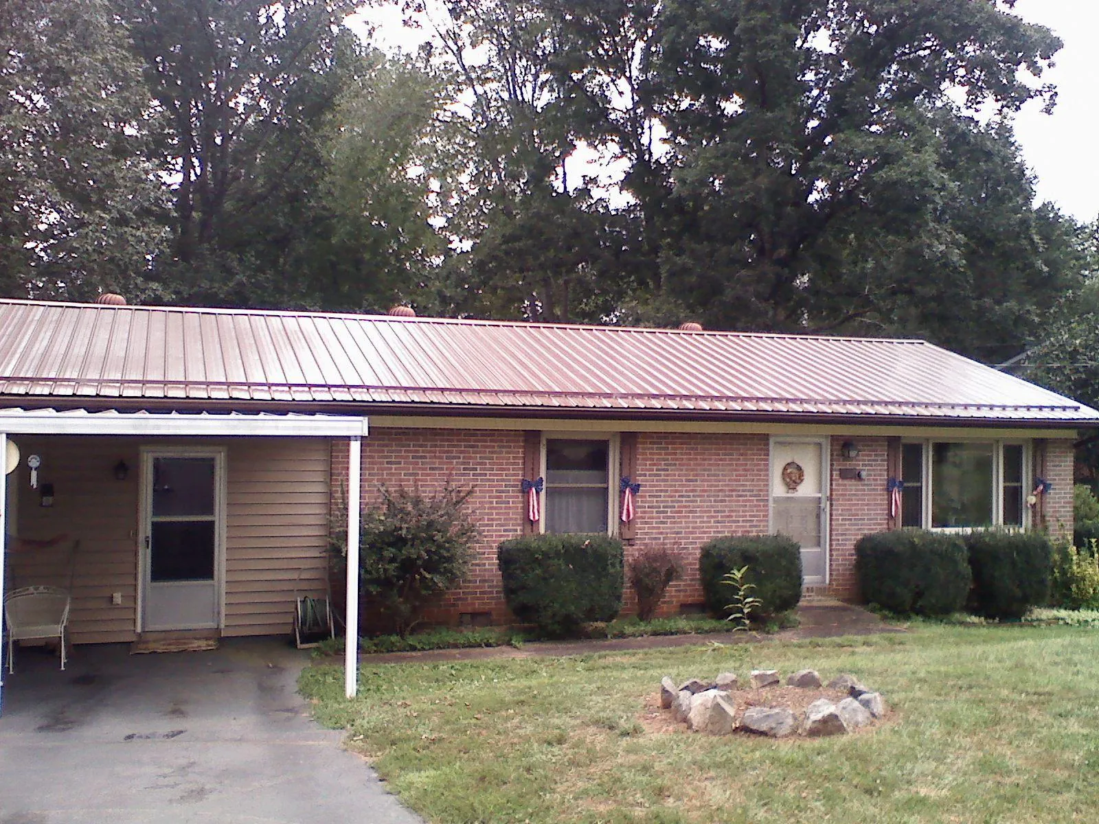 Bronze metal roof and carport on a brick ranch home — Roof Repair work by our crew in Newberry