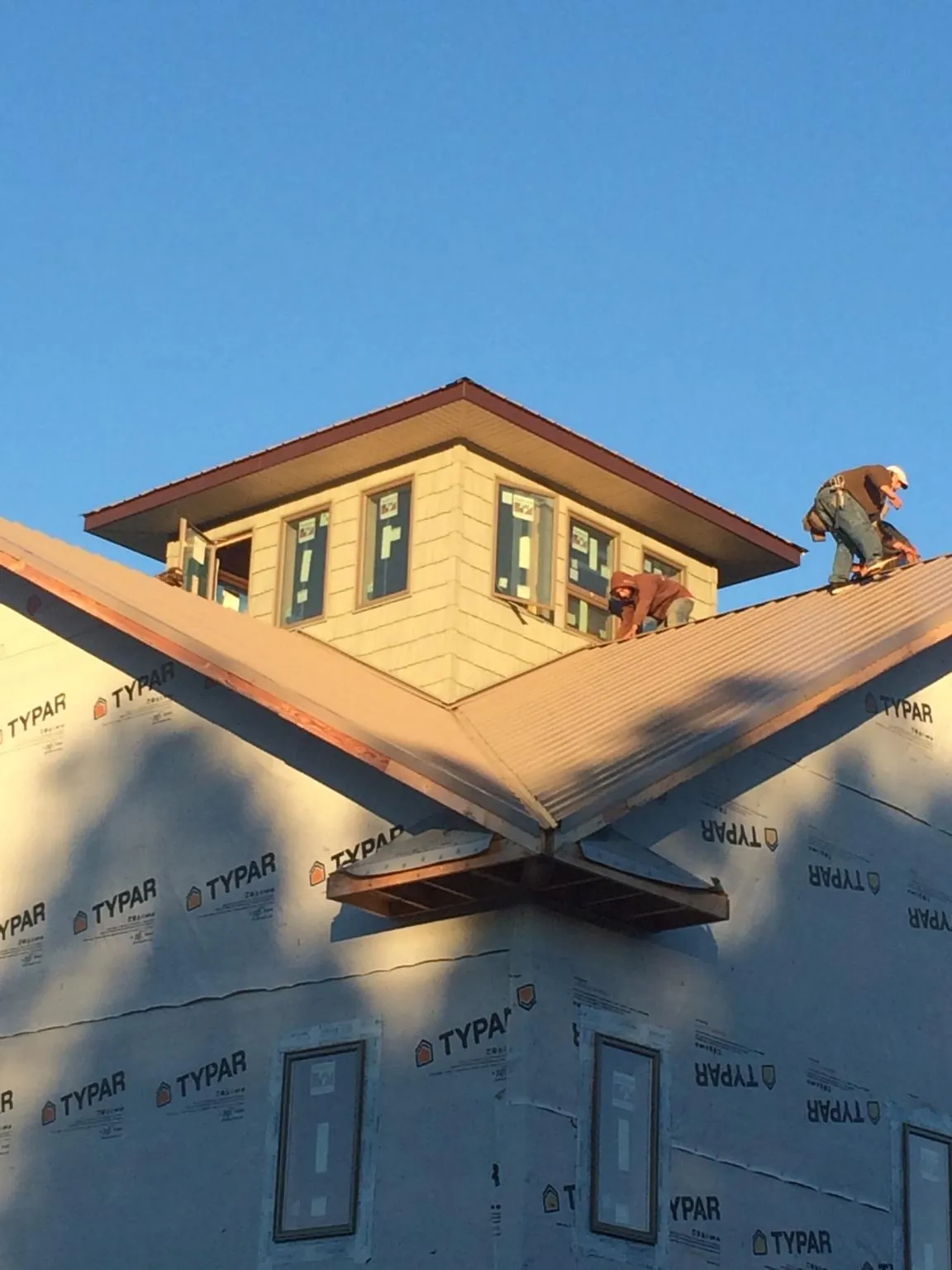 Roofers working around a rooftop cupola on a new metal roof at sunset — Roof Waterproofing in Newberry by Roofing Brothers